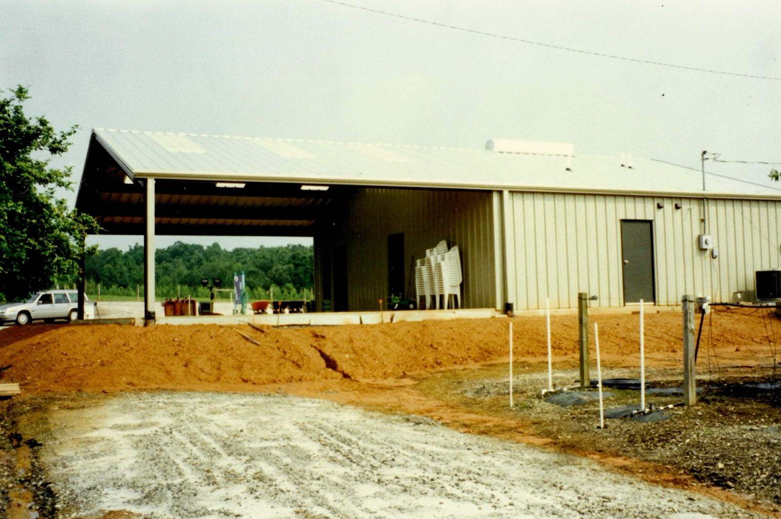 The metal nursery building and covered pavilion under construction on freshly graded red clay